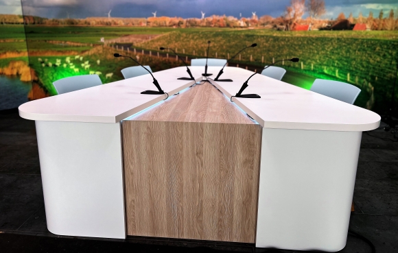 Moderne talkshowtafel met ingebouwde microfoons en houten afwerking in een corporate in-house studio, ontworpen door GetyourStudio