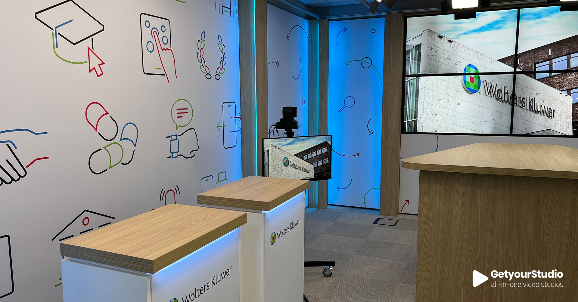 Corporate in-house studio met dubbele presentatiedesks en maatwerk inrichting in huisstijl van Wolters Kluwer